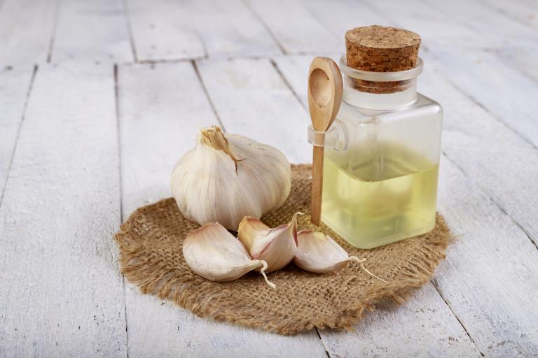 whole and chopped garlic next to a bottle of extract