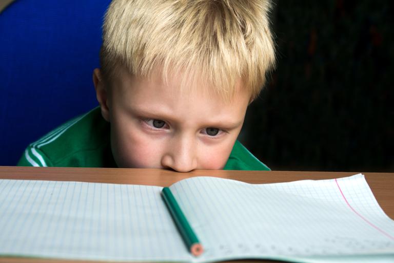 A child staring helplessly at his blank schoolwork