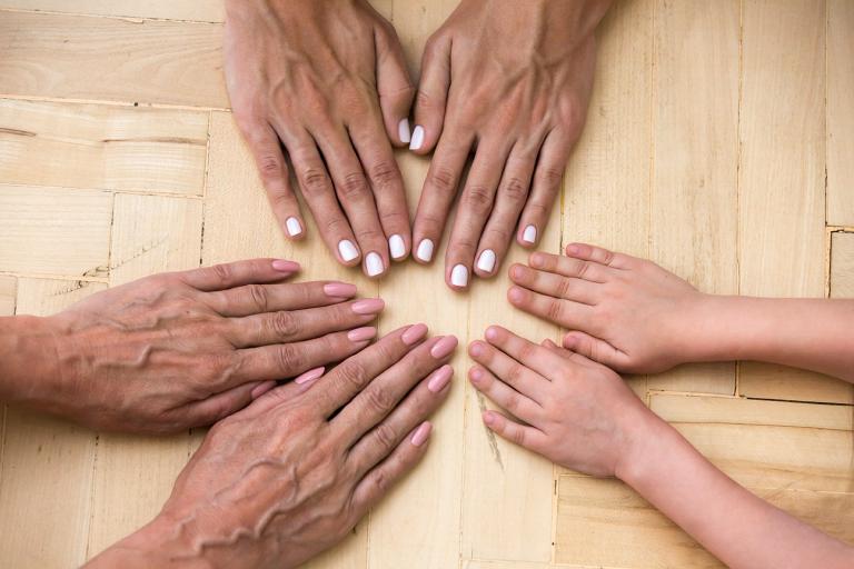 different generations of a family touching hands